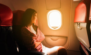 Woman traveling alone on plane in window seat