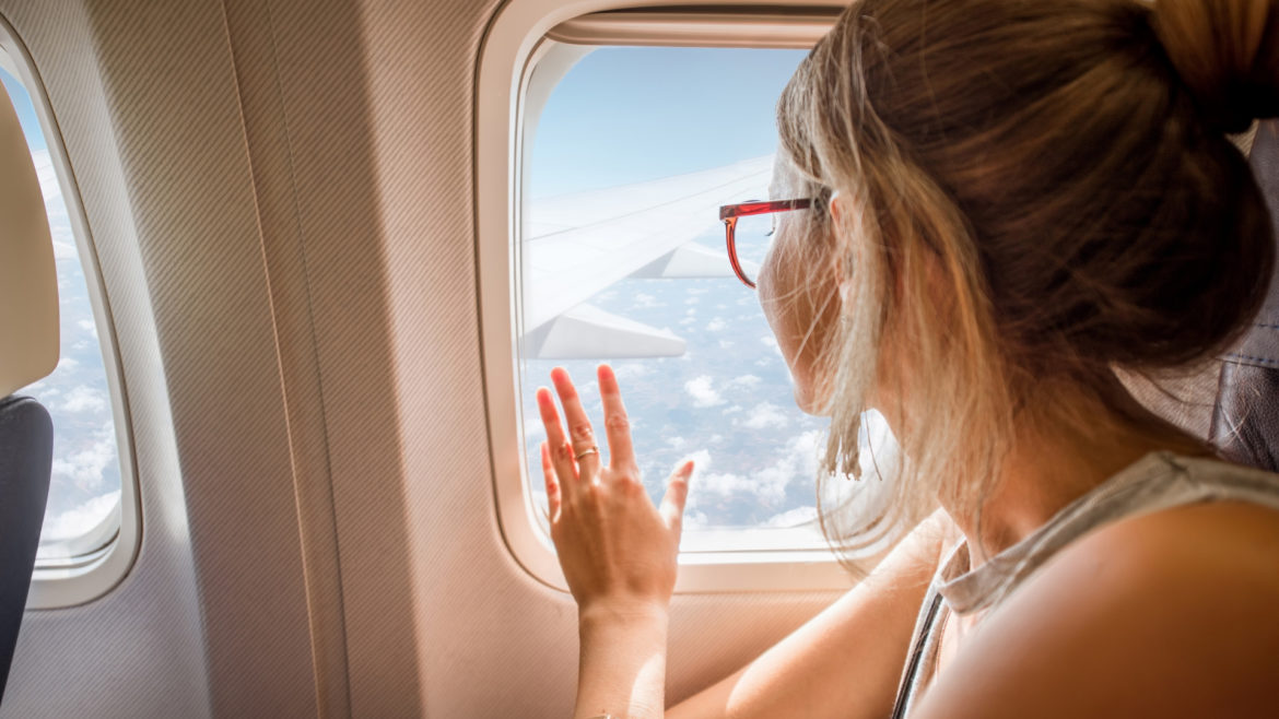 Young woman looking out window of airplane