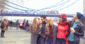 College students in London by Tower Bridge laughing | AIFS Study Abroad