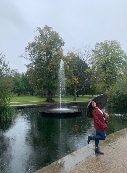 College student studying abroad in London poses by a pond in a park with an umbrella | AIFS Study Abroad