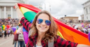 Young woman holding LGBTQIA+ flag in Europe | AIFS Study Abroad