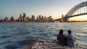 Two young people sitting beside the Sydney Harbor in Sydney, Australia