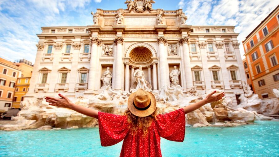 Feliz viajante feminino de frente para a fonte Trevi em Roma, Itália com os braços para fora