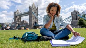 Young woman studying in front of Tower Bridge in London, England