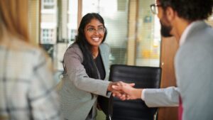 Young professional woman shaking hands with potential employer during interview