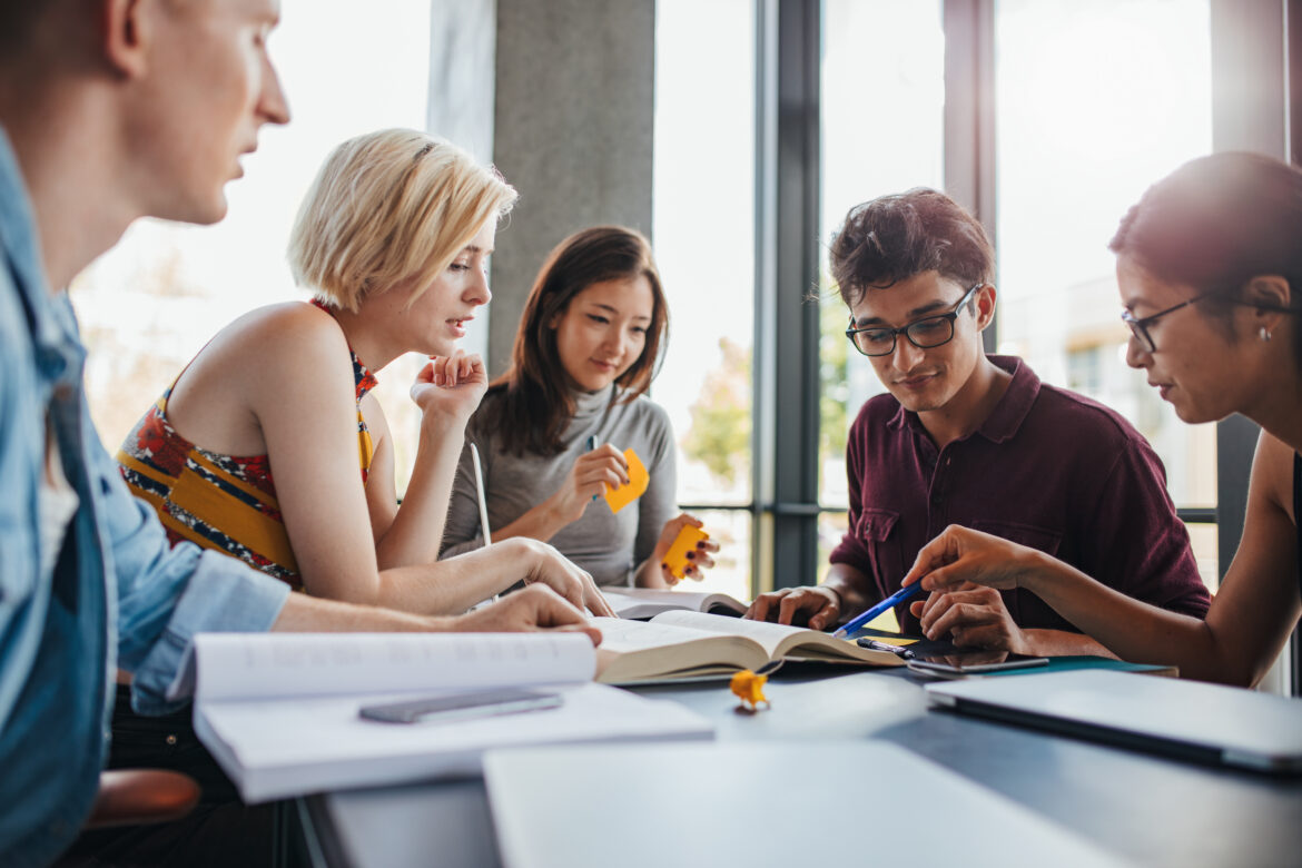 group of young people sitting at table reading books