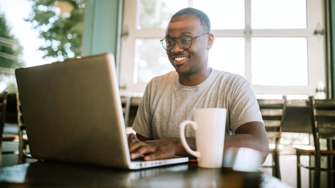 Man working remotely on laptop with cup of coffee