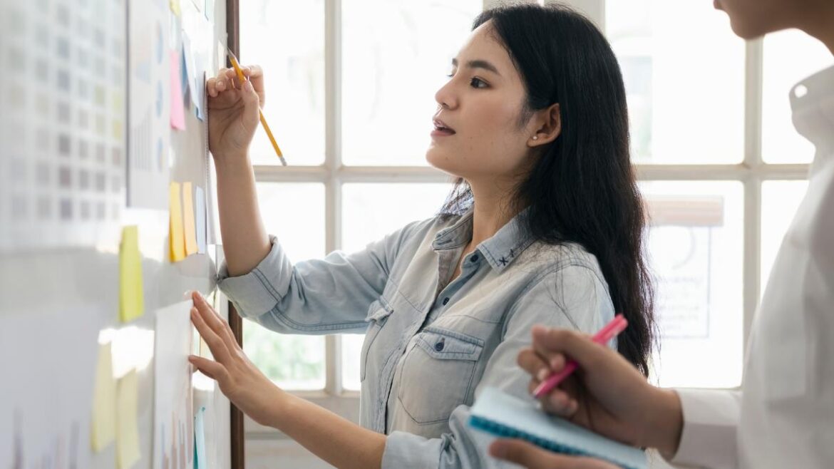 Female intern writing on white board organizing project at work
