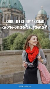 Pin image: Young woman traveling alone in Berlin, Germany with text overlay "should i study abroad alone or with a friend?"