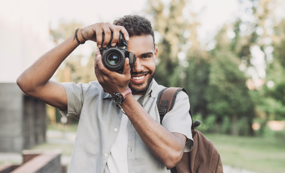 Young man photographer takes photographs with dslr camera in a c