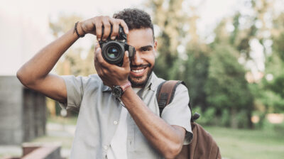 Young man photographer takes photographs with dslr camera in a c