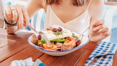 woman having meal with greek salad Horiatiki in restaurant vegetarian